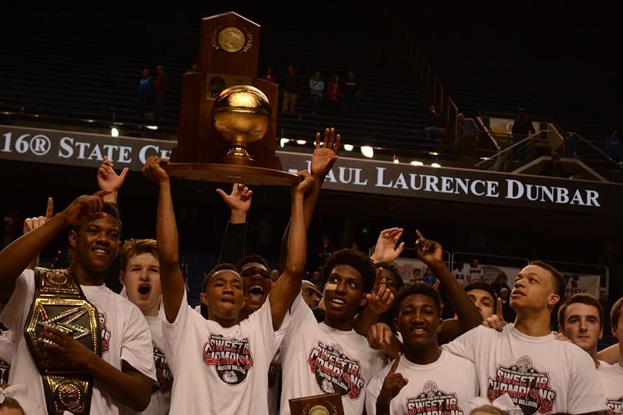 Senior Jordan Lewis holds the championship trophy while his teammates celebrate the win