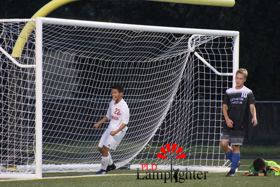 Kevin Jing, #22 is excited after a goal is scored while the opposing Lexington Christian players look defeated.