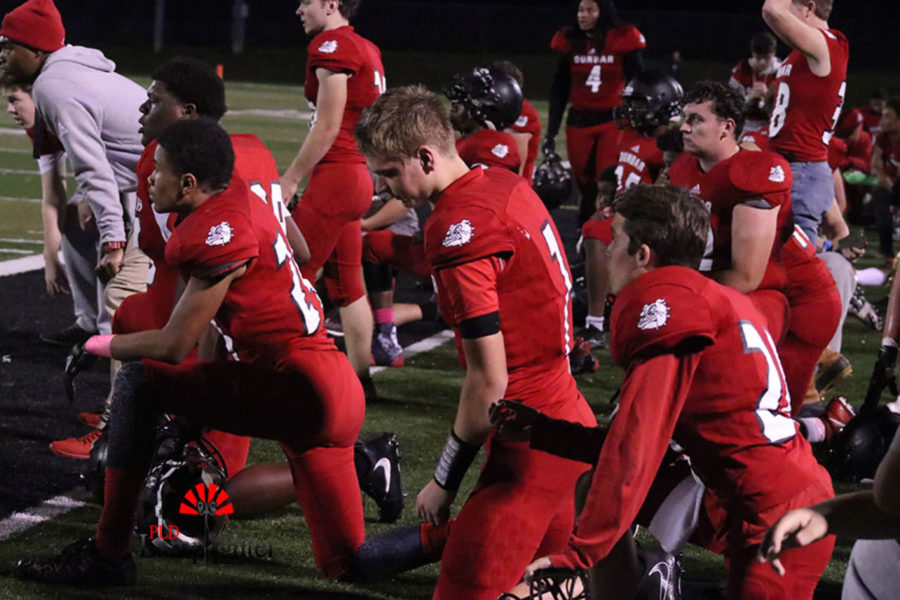 Dunbar football players take a knee for injured teammate senior Tyler Browning. 
