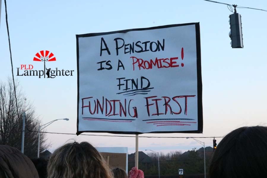 A sign is raised by a Dunbar teacher during the walk-in before school. A pension is a promise! Find Funding First.
