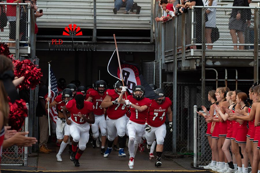 In 2018, Dunbars football team showing their school spirit as they rush to the field with the school flag.
