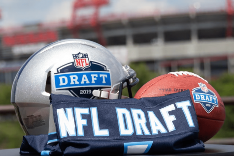 A helmet with the 2019 NFL Draft Logo lying next to an NFL Draft jersey and an NFL Draft football.