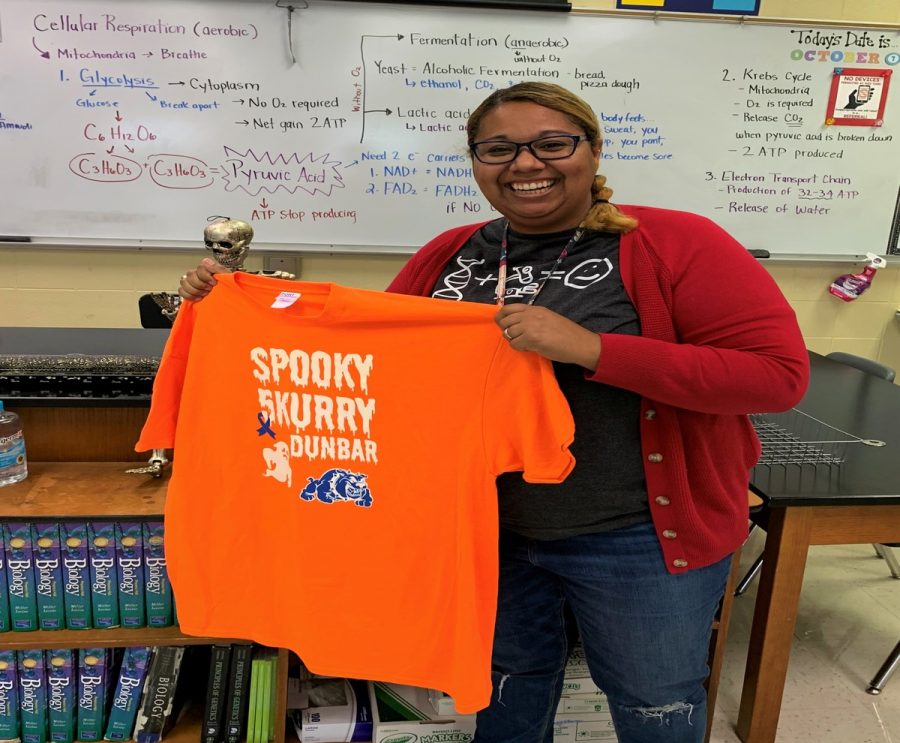 Mrs. Newsome holding a Spooky 5kurry T-shirt.